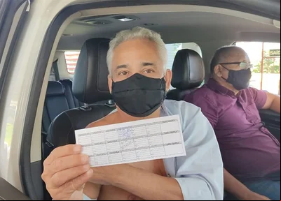 Robert Rios segurando a carteira de vacinação