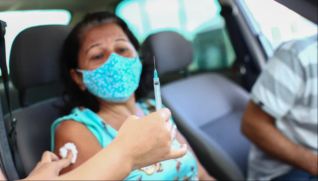 Senhora toma sua primeira dose da vacina